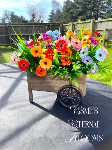 A wooden cart filled with colourful flowers on a sunny outdoor setting.