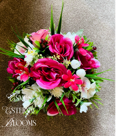 A vibrant bouquet featuring pink roses, white flowers, and lush green foliage.